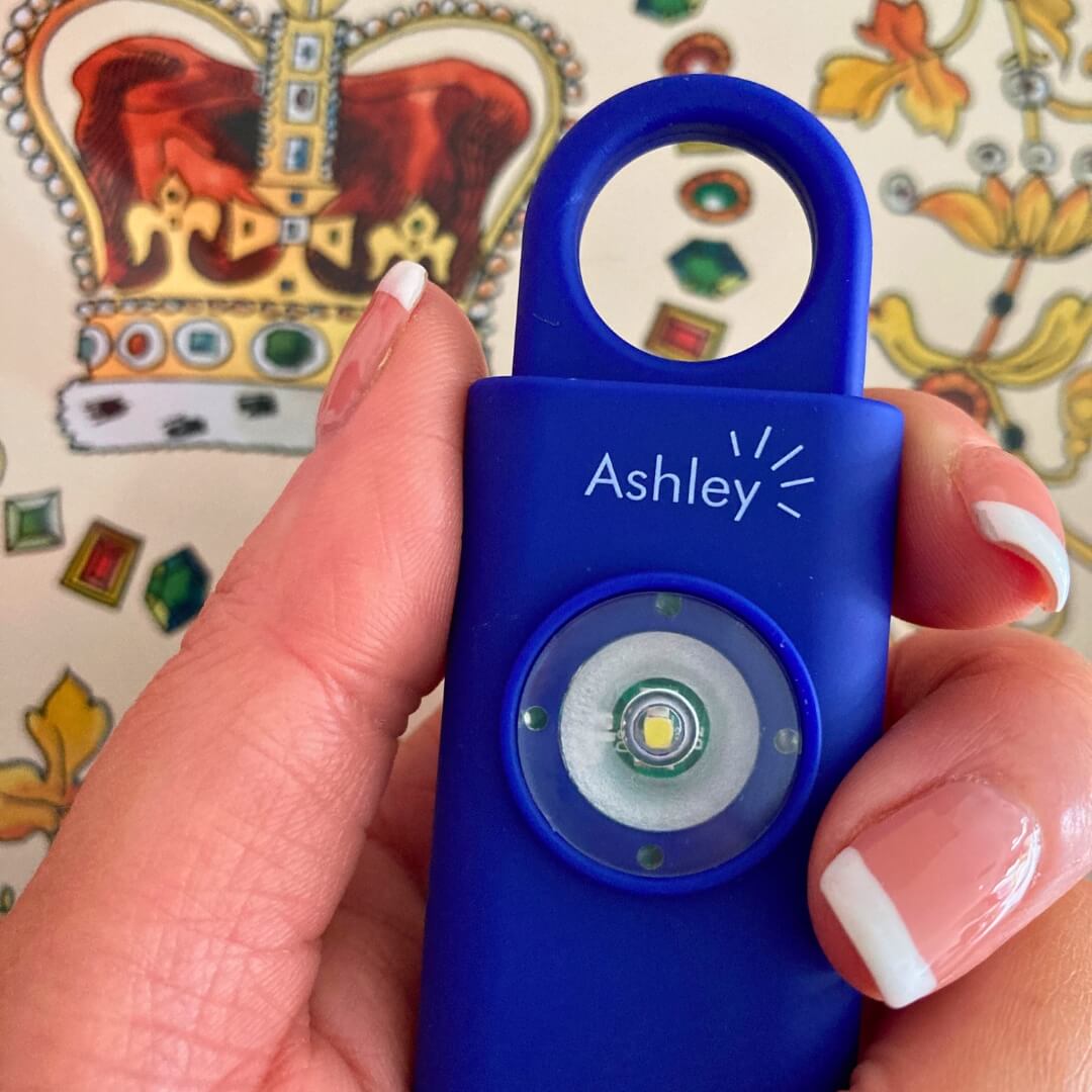 Hand holding a navy Ashley personal attack alarm